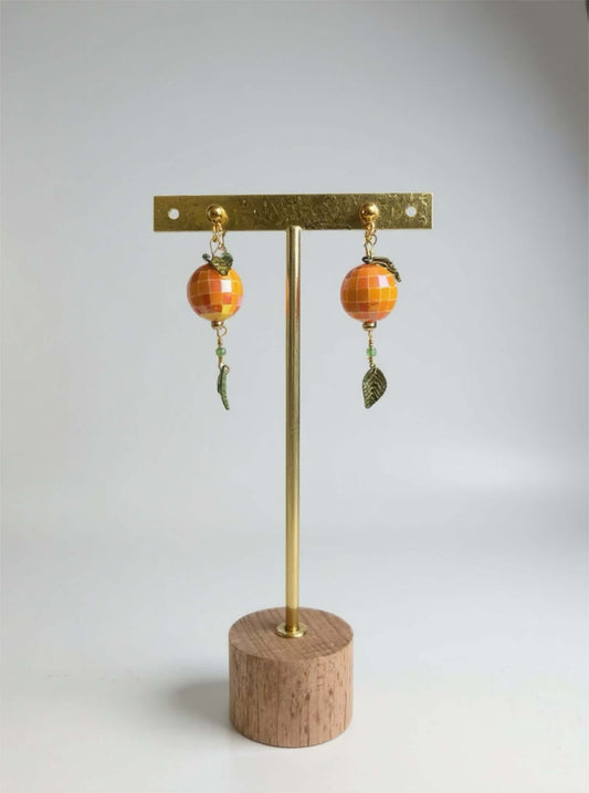 Un bijou vitaminé signé Mieleonor. Boucles disco orange - acier inoxydable, une pièce éclatante en acier inoxydable inspirée de vos journées et du plaisir de briller.